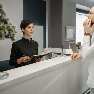 A receptionist assists a patient with a toothache at a dental clinic's front desk.