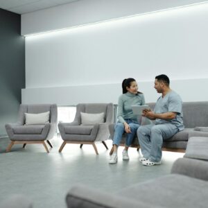 Doctor and patient discussing health in a modern waiting room with digital tablet.