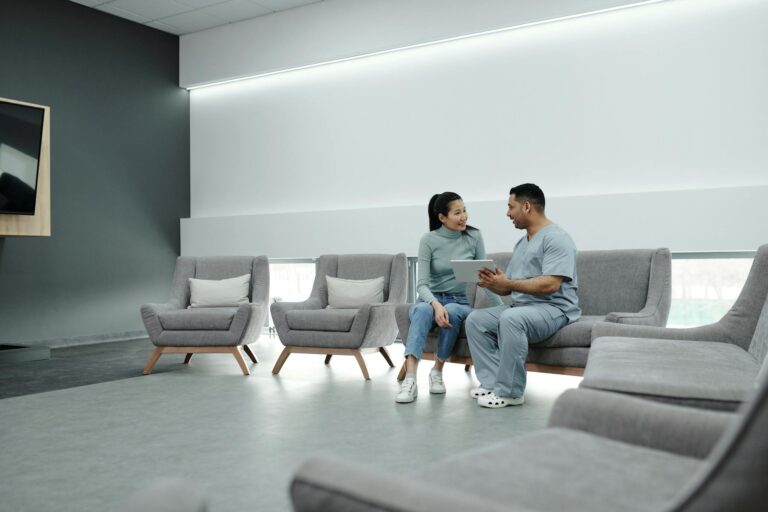 Doctor and patient discussing health in a modern waiting room with digital tablet.