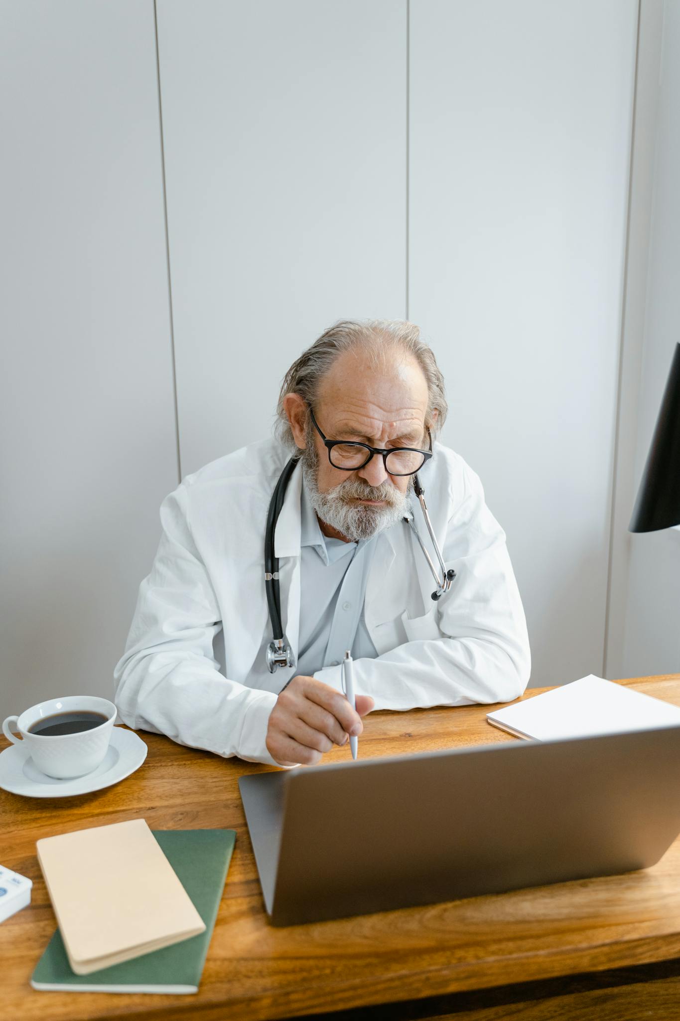 Elderly doctor focusing on an online consultation in a medical office setting.