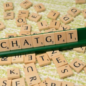 Scrabble game spelling 'CHATGPT' with wooden tiles on textured background.